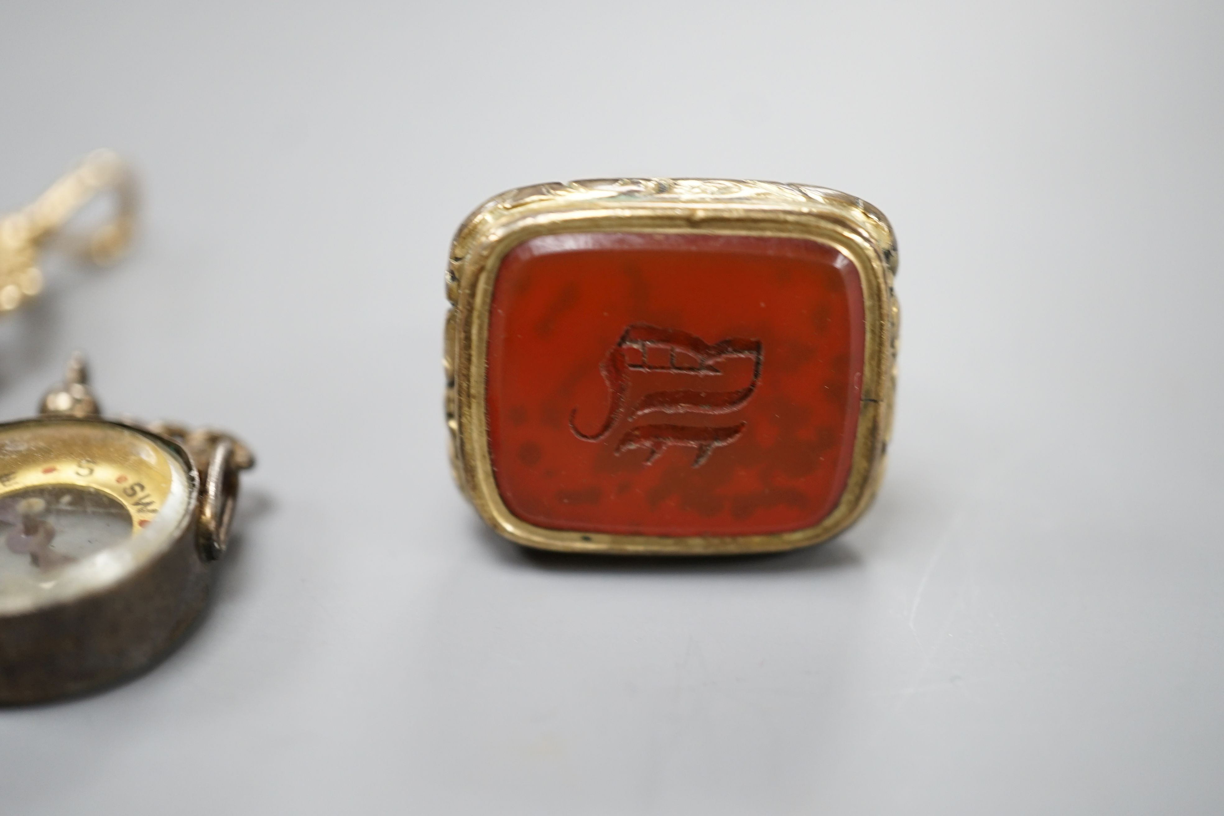 A modern 9ct gold and carnelian set swivelling fob seal, 40mm, a Victorian gold plated and carnelian set fob seal and a white metal mounted (stamped silver) compass fob.